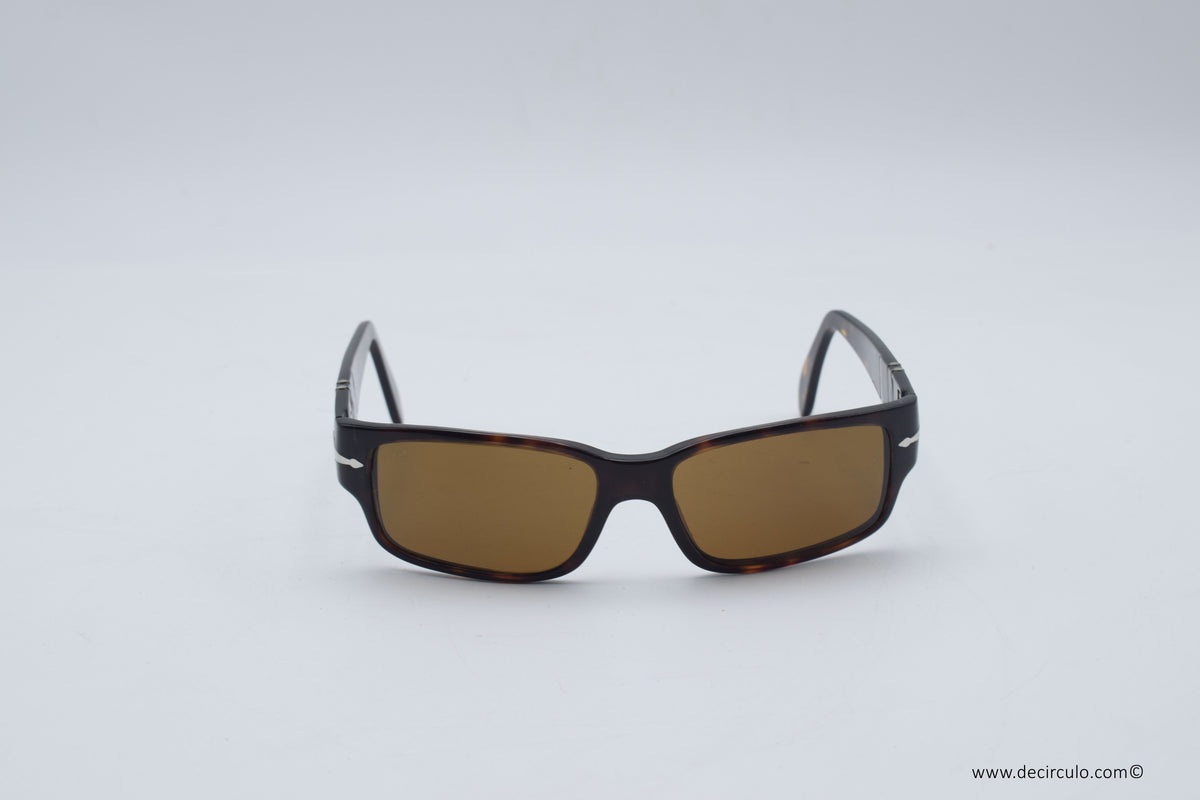 A pair of rectangular sunglasses with a dark tortoiseshell frame and brown tinted lenses, photographed on a light gray background.