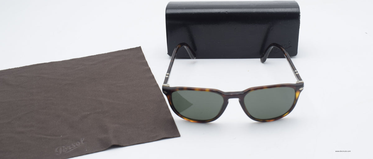 A pair of vintage-style sunglasses with tortoiseshell frames and green lenses, displayed next to a black hard case and a brown microfiber cleaning cloth on a white background.