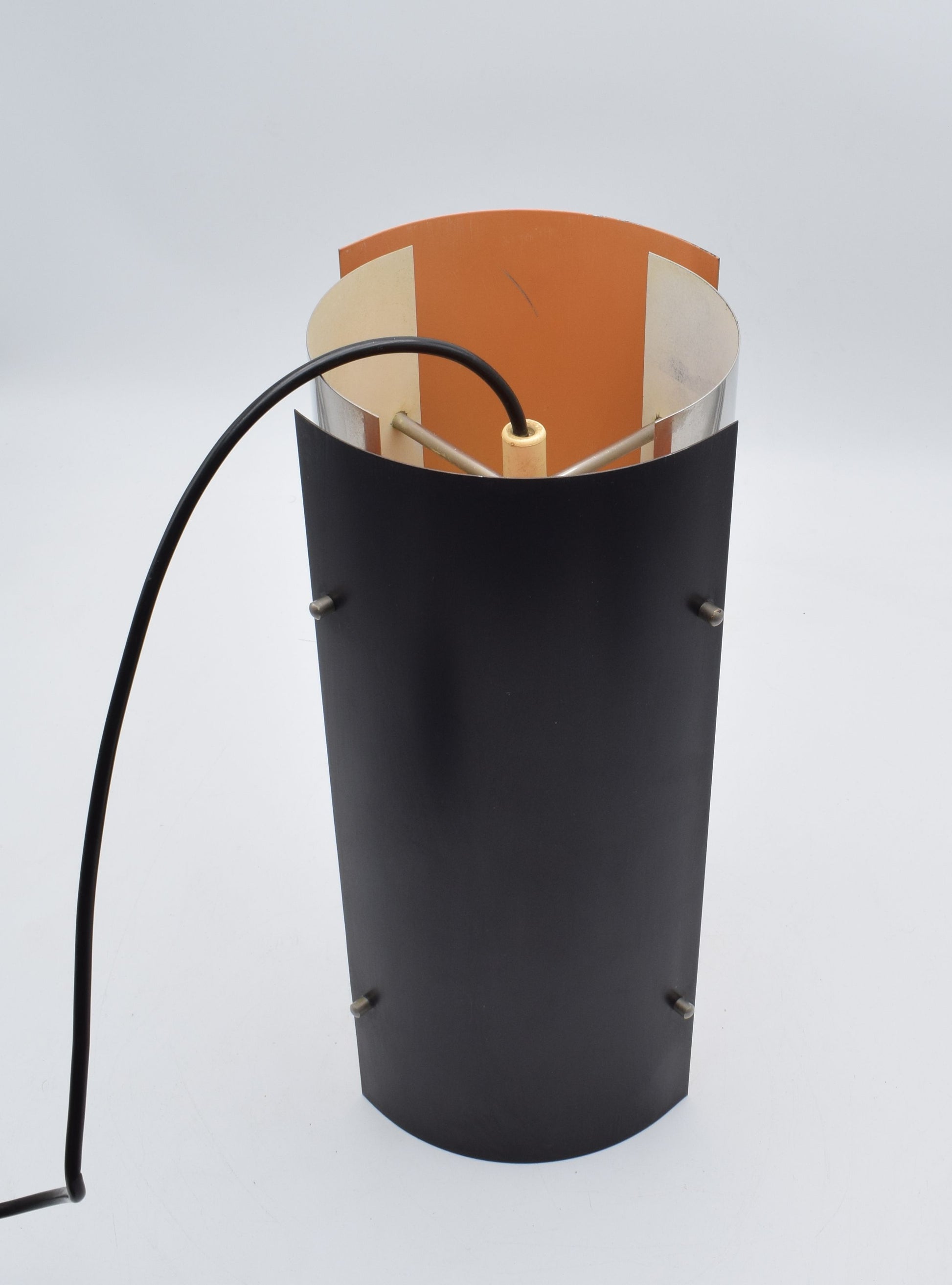 1970s Scandinavian pendant lamp with two black and two chrome quarter‑cylinder plates, chrome rods, and warm orange inner lacquer creating a directional glow