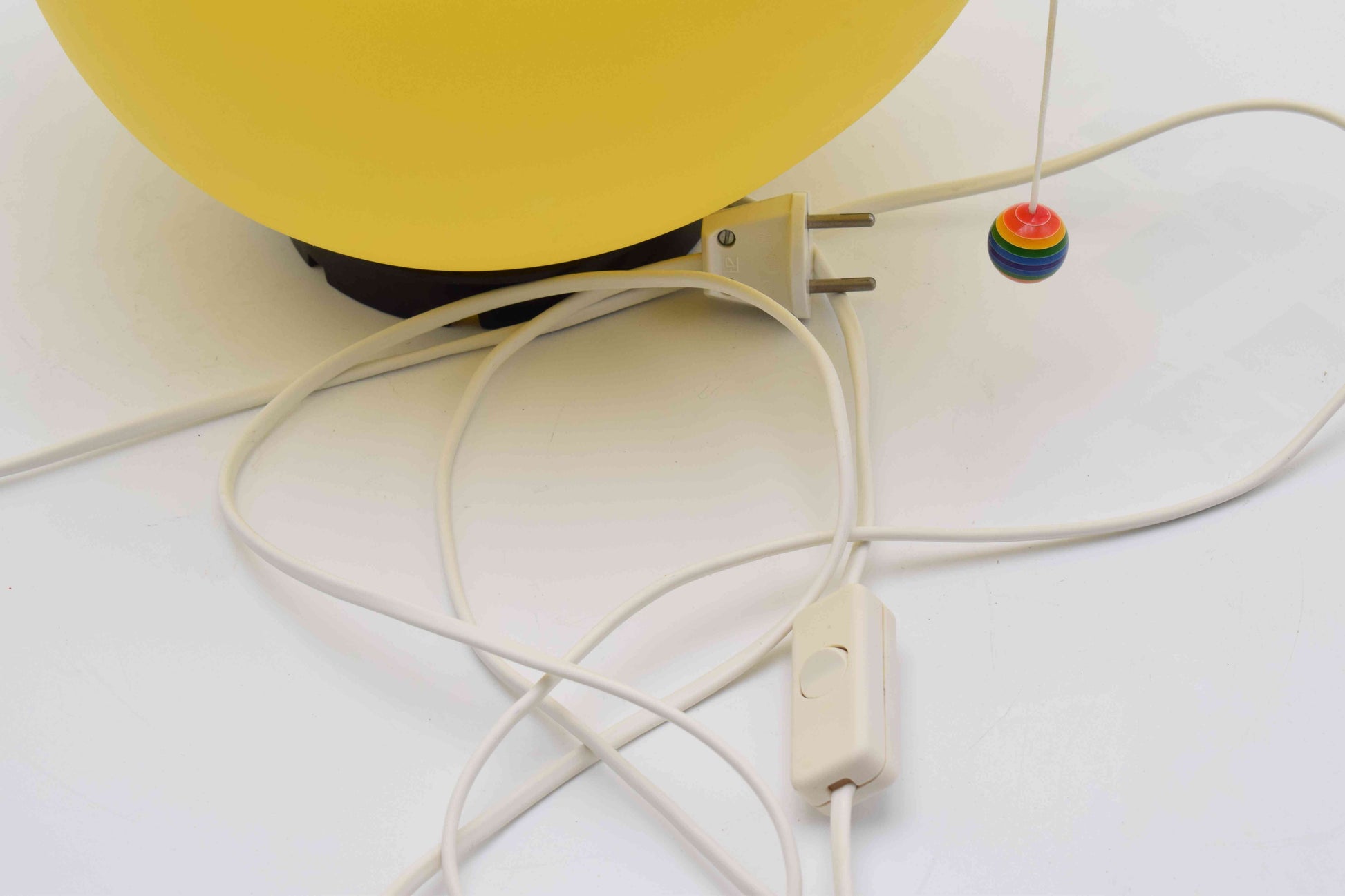 Close-up of a power adapter with a colorful plug on a white surface