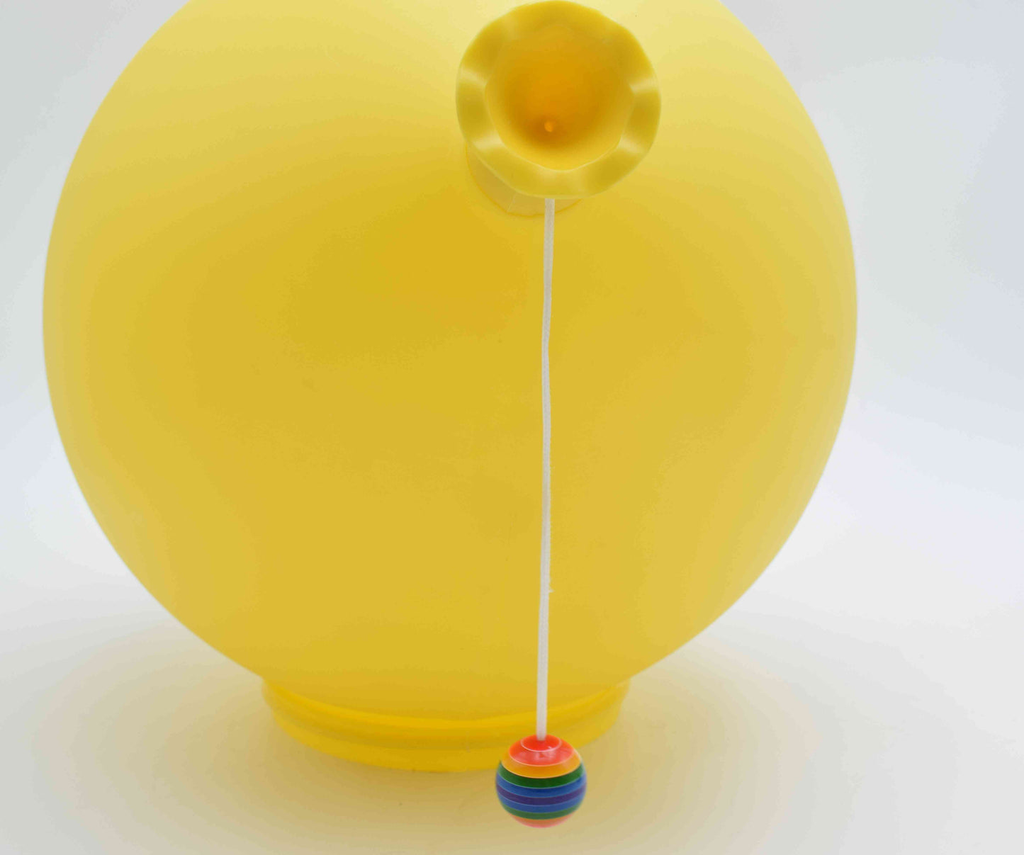 Yellow balloon with a colorful string holder on a white background