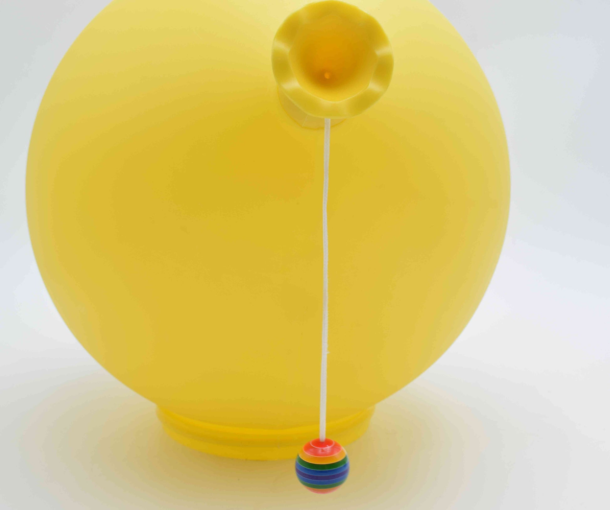 Yellow balloon with a colorful string holder on a white background