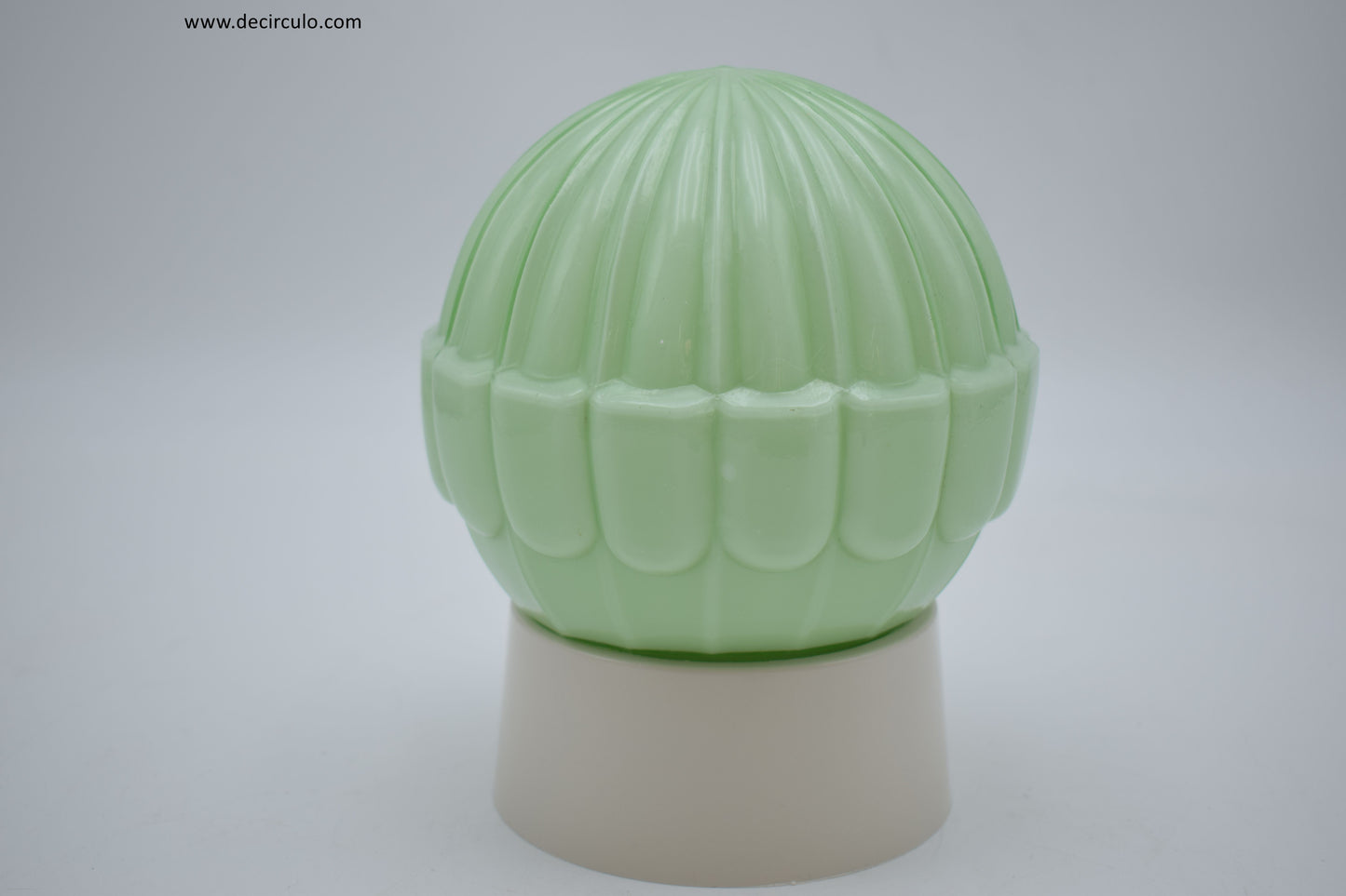 Green ceramic vase with ribbed design on a white background