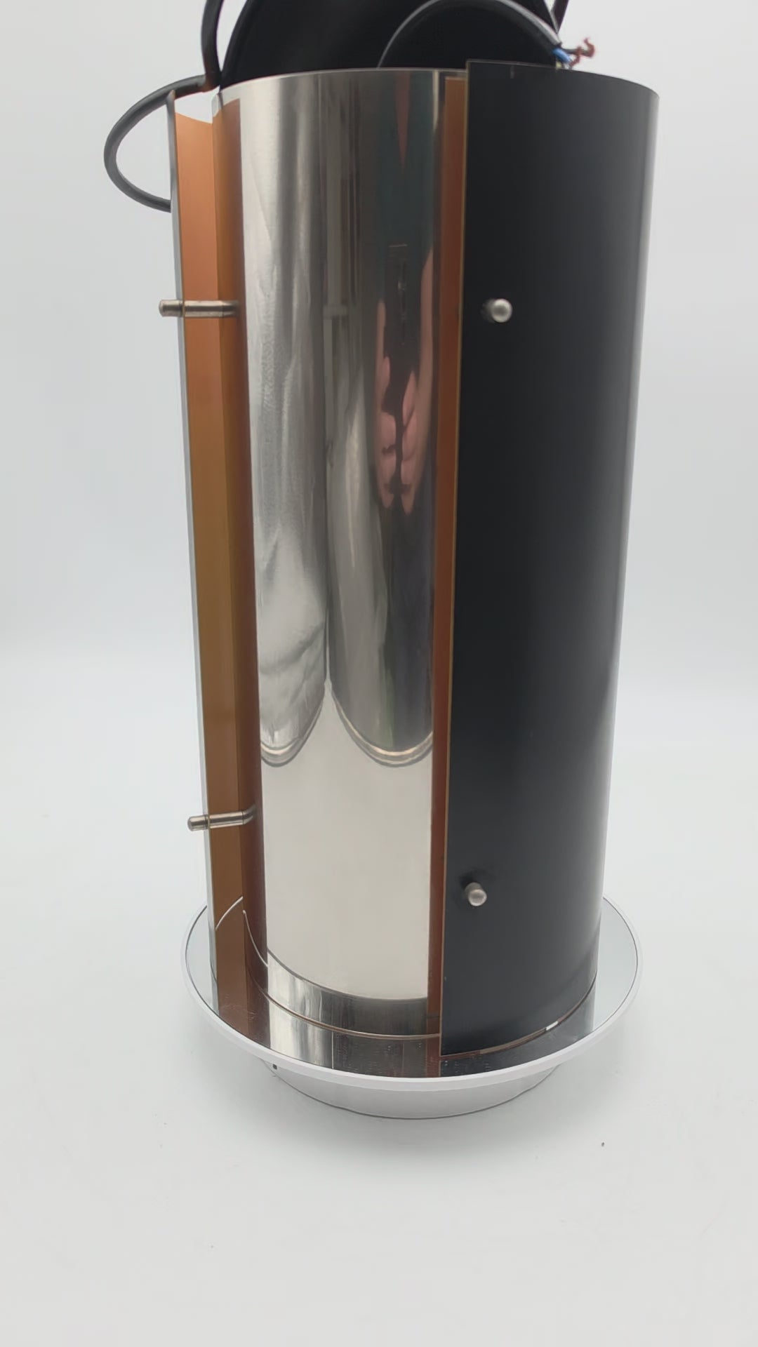 1970s Scandinavian pendant lamp with two black and two chrome quarter‑cylinder plates, chrome rods, and warm orange inner lacquer creating a directional glow