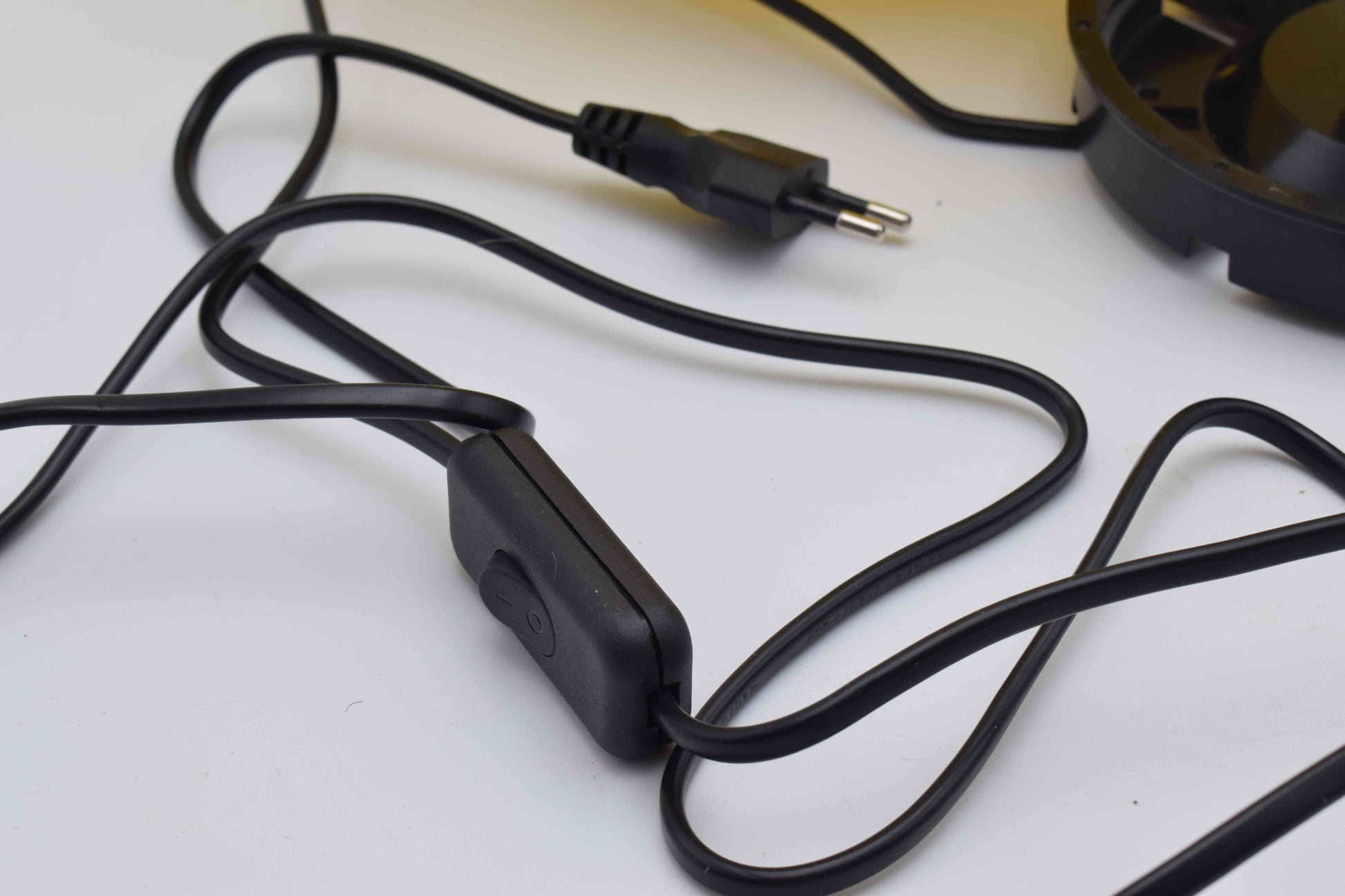 Black electrical cord with plug on a white surface