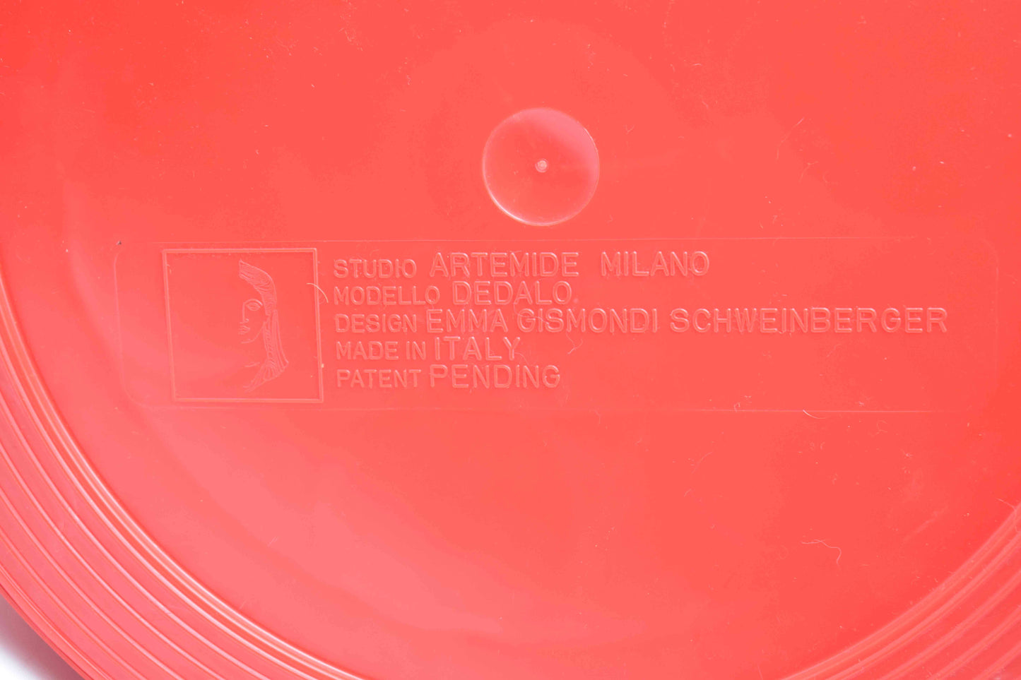Close-up of a red product with 'Studio Artemide Milano' branding and text.