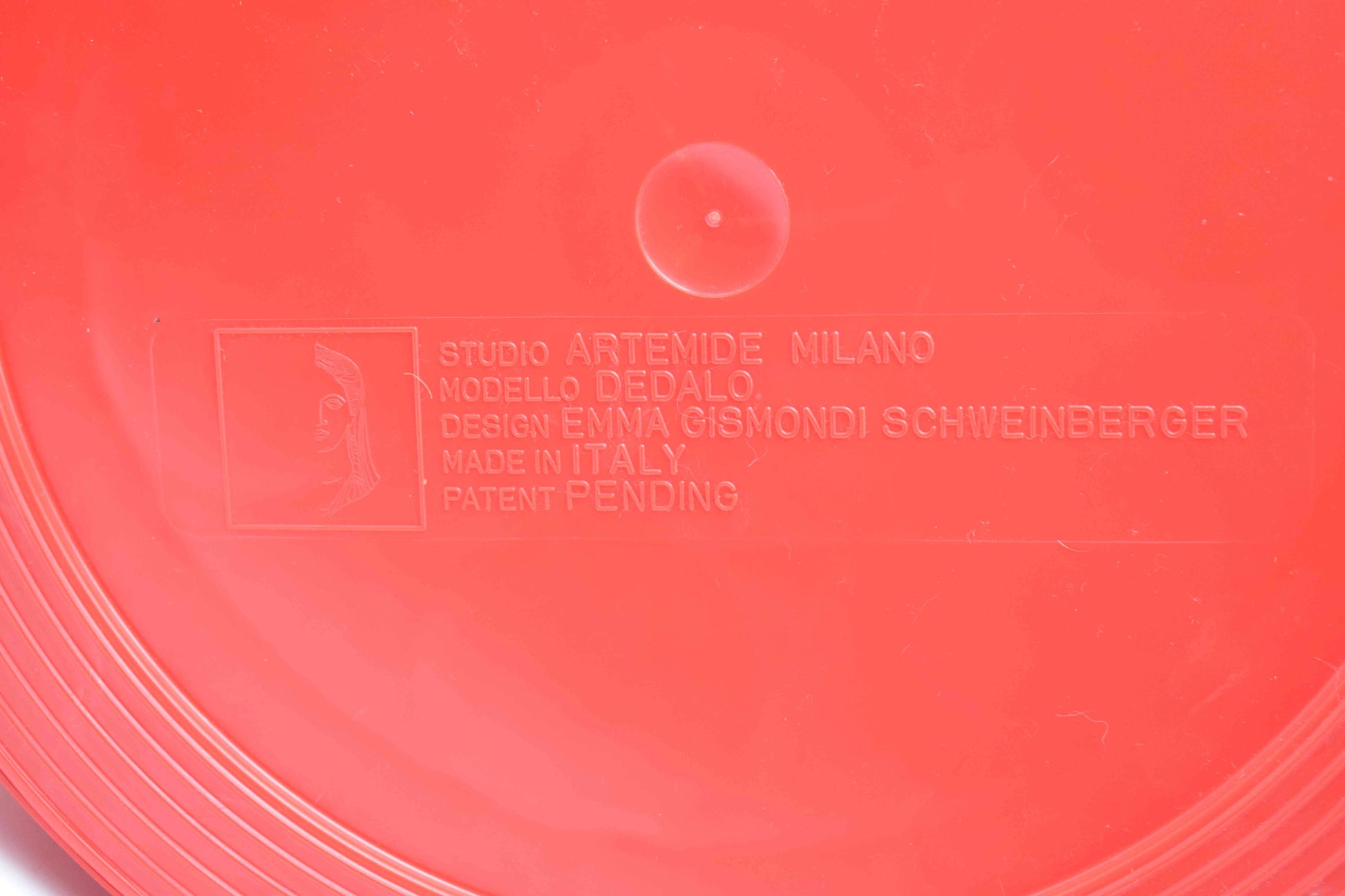 Close-up of a red product with 'Studio Artemide Milano' branding and text.