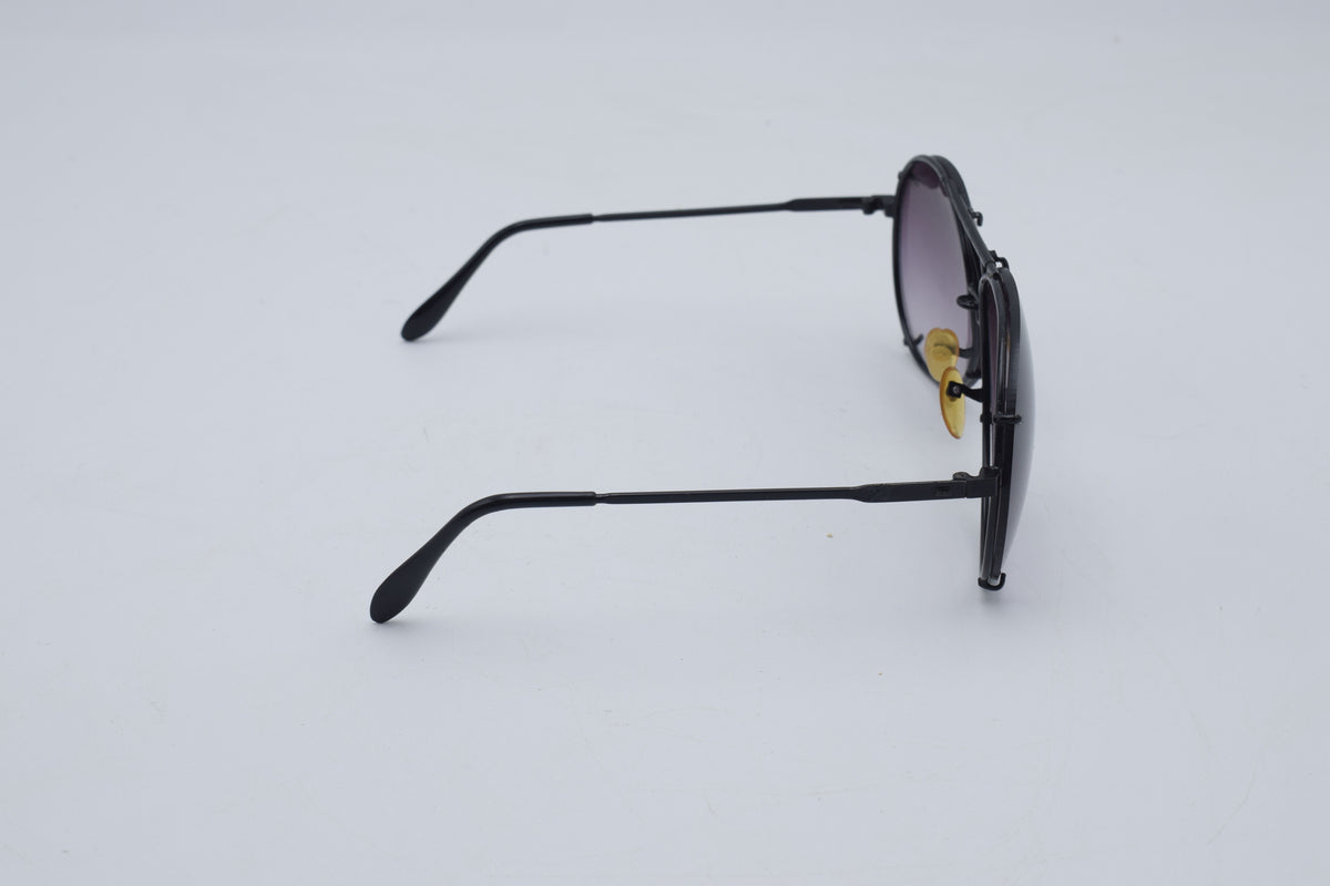 A pair of black metal round-frame sunglasses with dark lenses, shown from a side profile view on a light gray background.