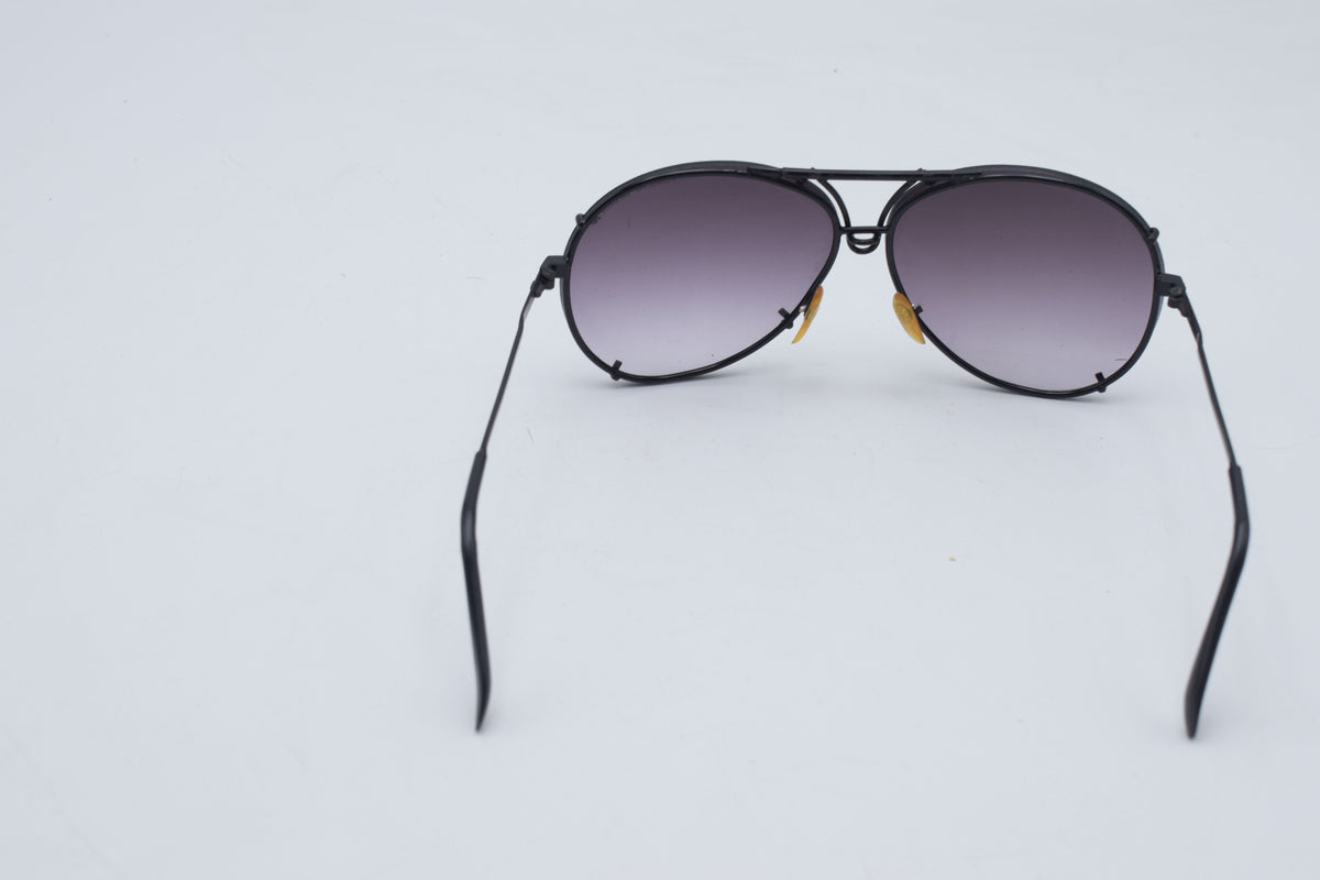 Black aviator sunglasses with gradient purple-tinted lenses, shown from the back on a light gray background.