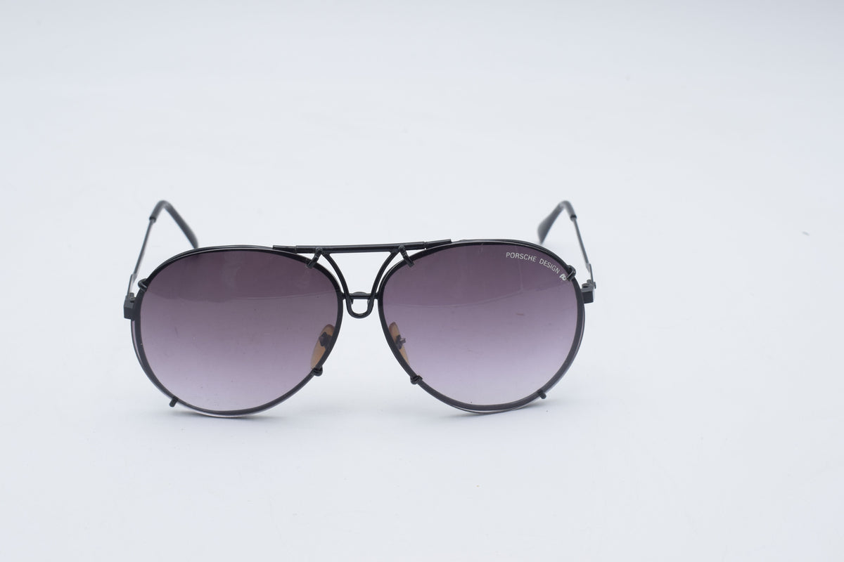 A pair of aviator-style sunglasses with a thin black metal frame and gradient gray-purple lenses, shown against a plain white background.